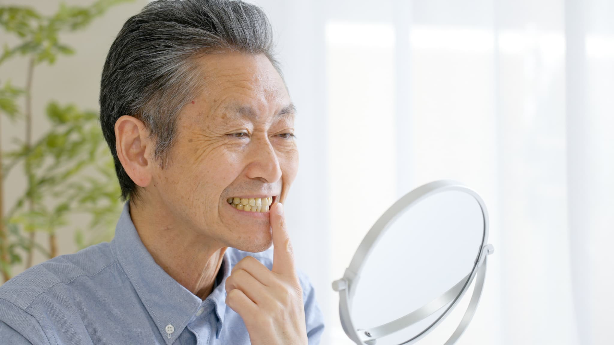 入れ歯の寿命かなと鏡を見ながら考える男性