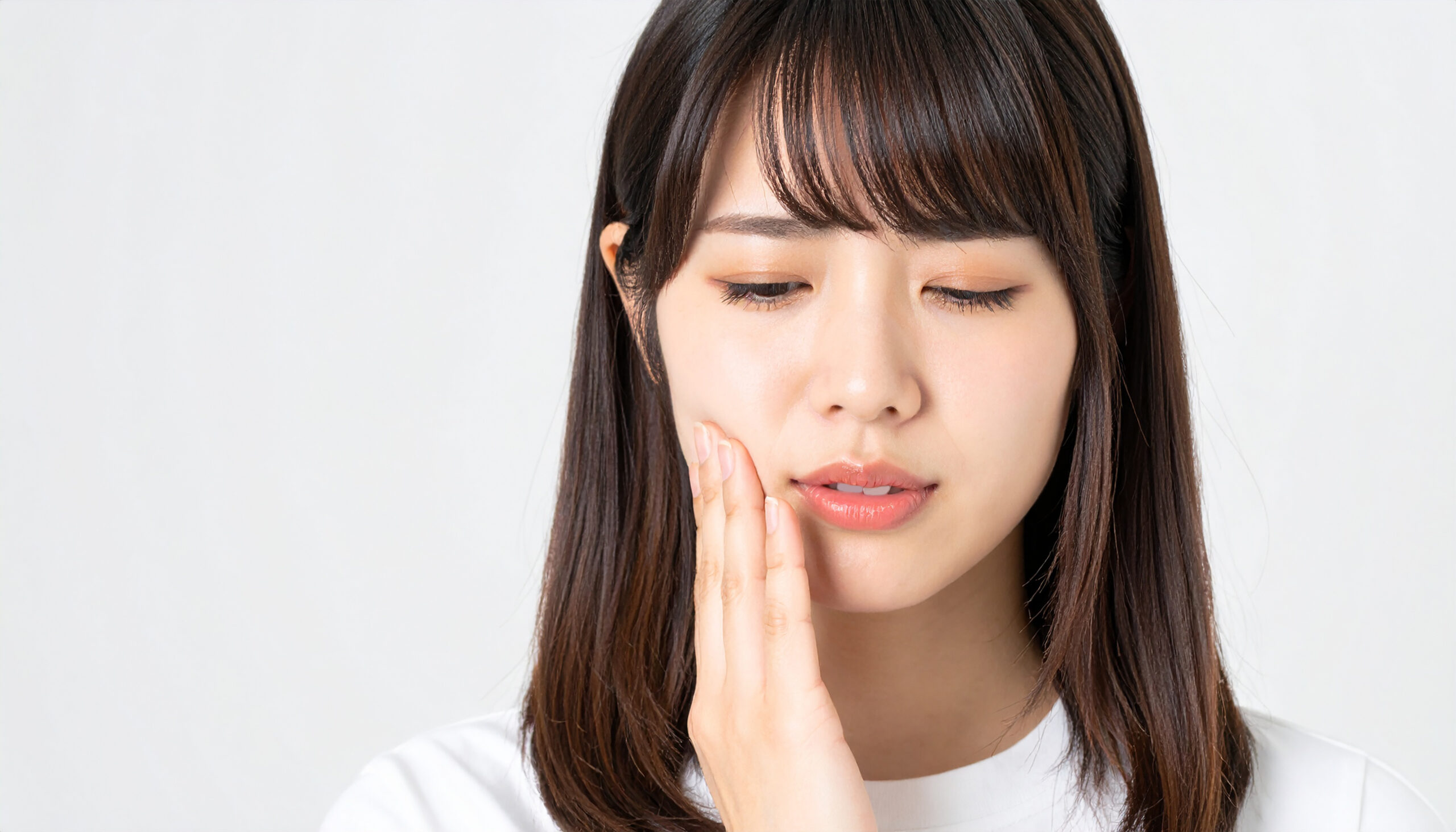 インプラント治療後に腫れた顔を押さえる女性